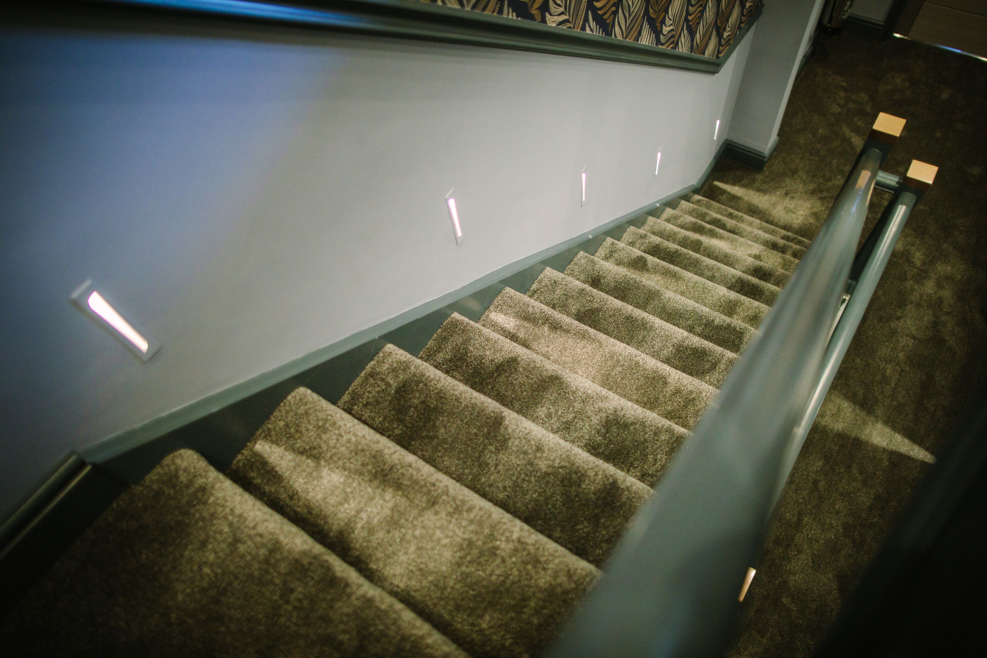 A carpeted staircase with a handrail and a wall with a patterned design.