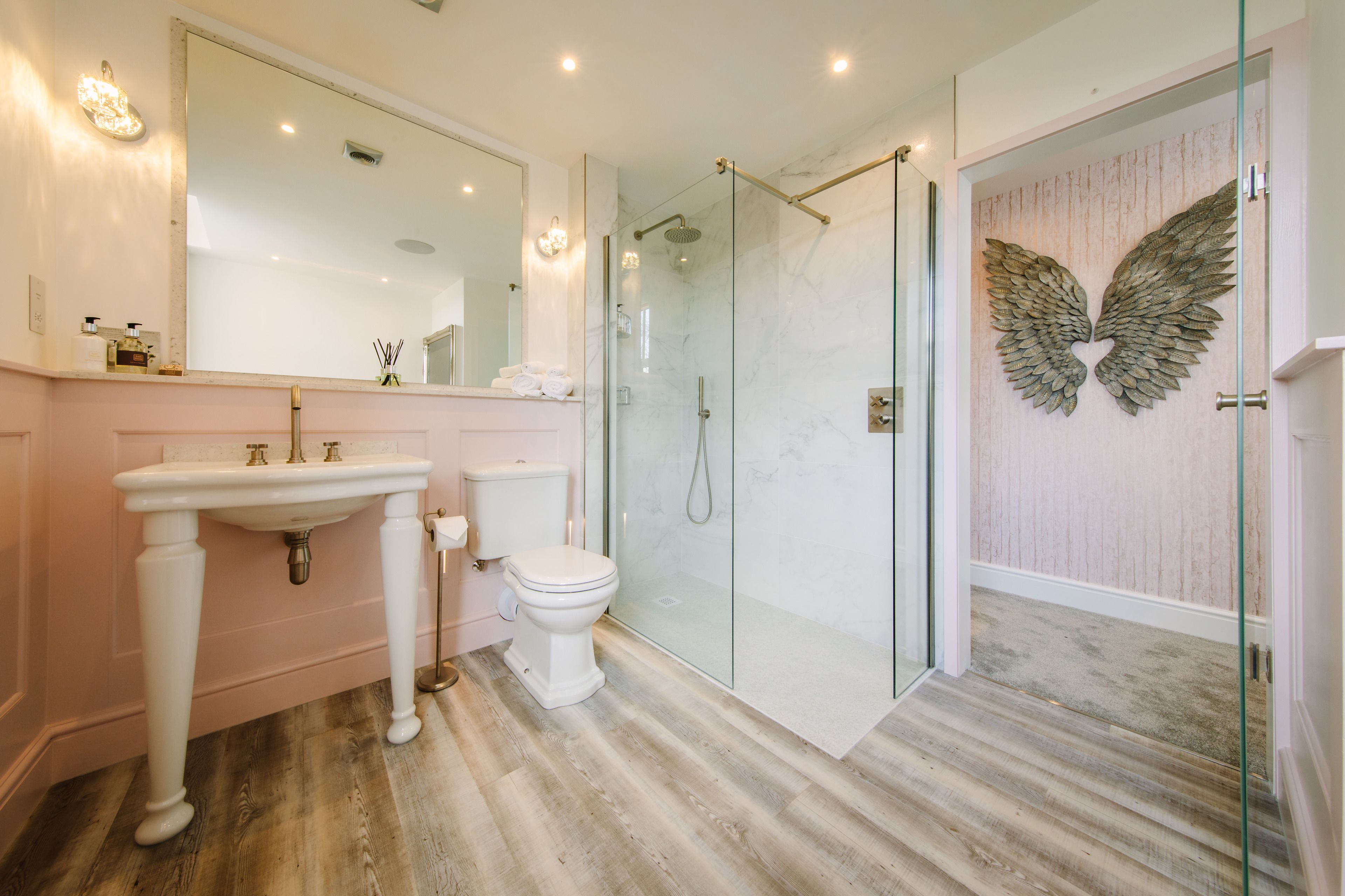 A bathroom with a glass shower enclosure, a white sink, and a toilet.