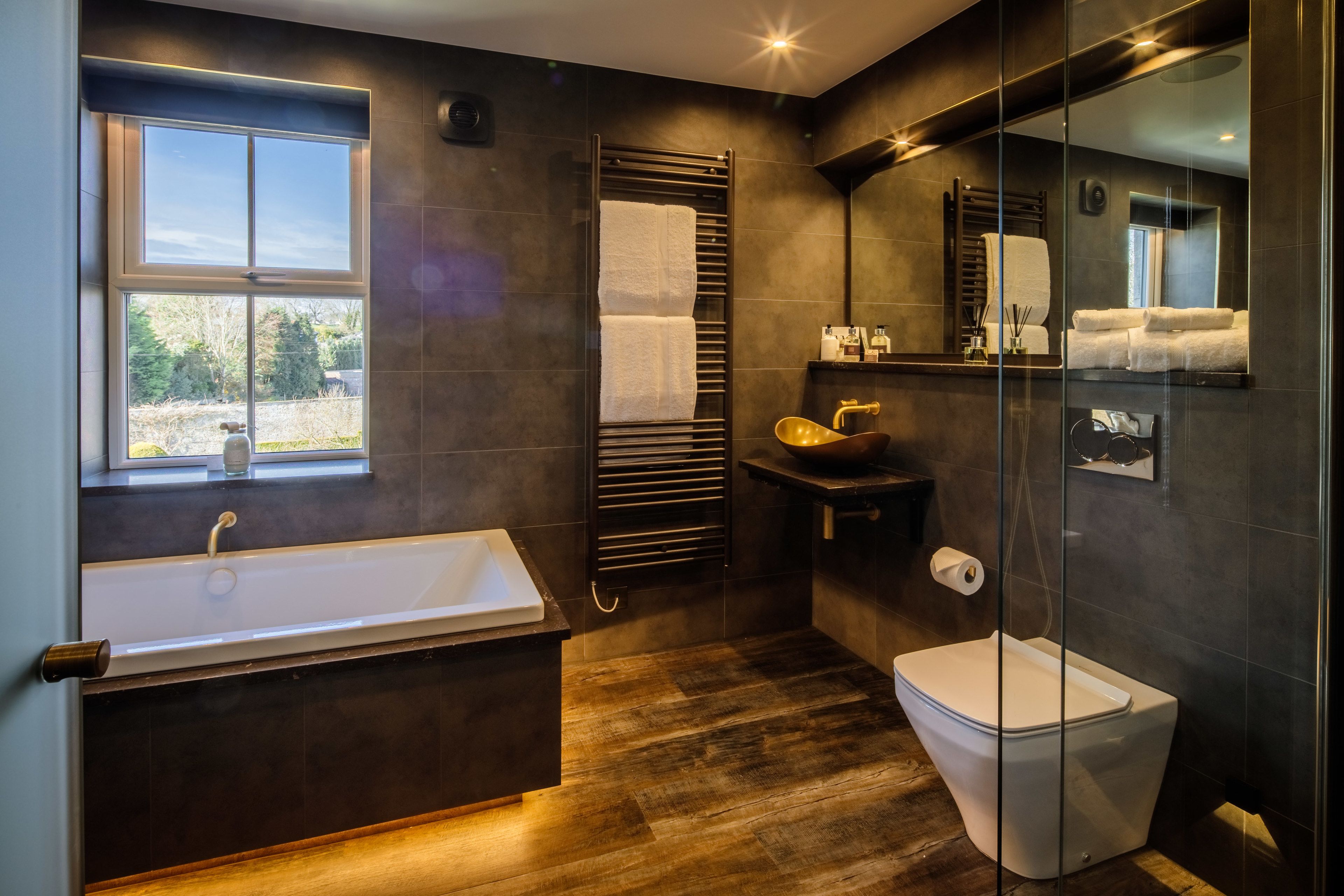 A modern bathroom with a bathtub, toilet, and a large mirror.