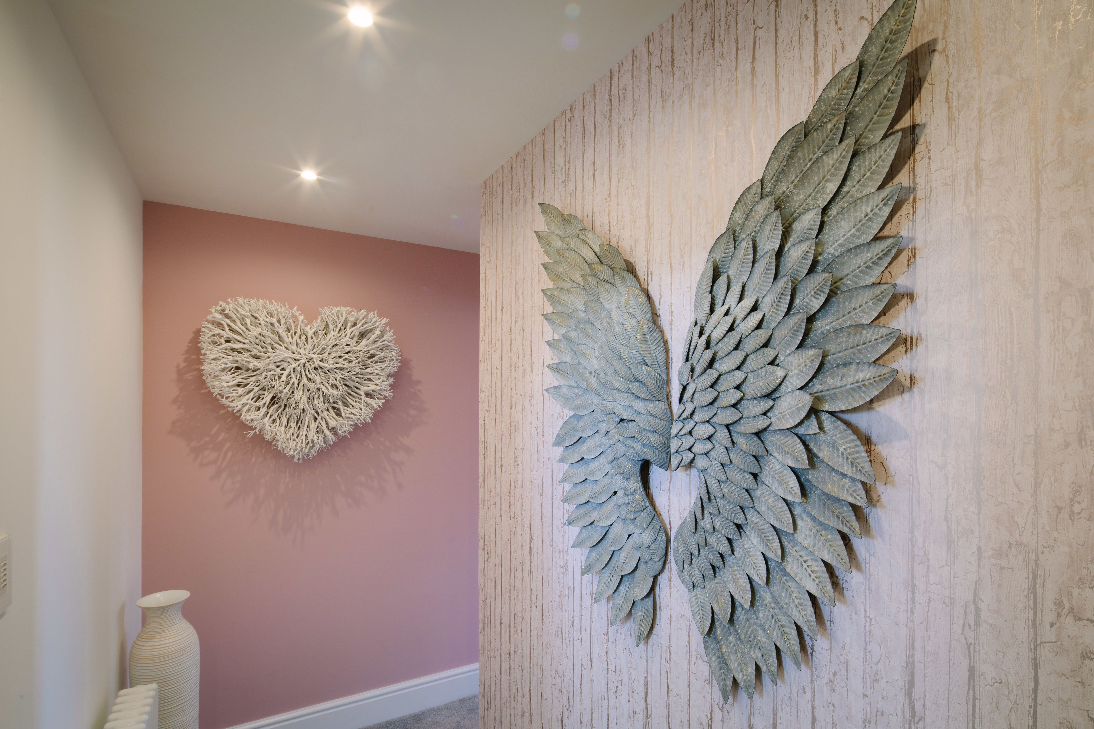 Una habitación con pared de madera, un ala decorativa grande y un adorno de pared con forma de corazón.