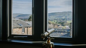 A telescope on a tripod in front of a window with a view of a rural landscape. - Absoluxe Suites (Carnforth)