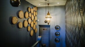 A hallway with a wooden wall design, a hanging light fixture, and a door with a sign. - Absoluxe Suites (Carnforth)