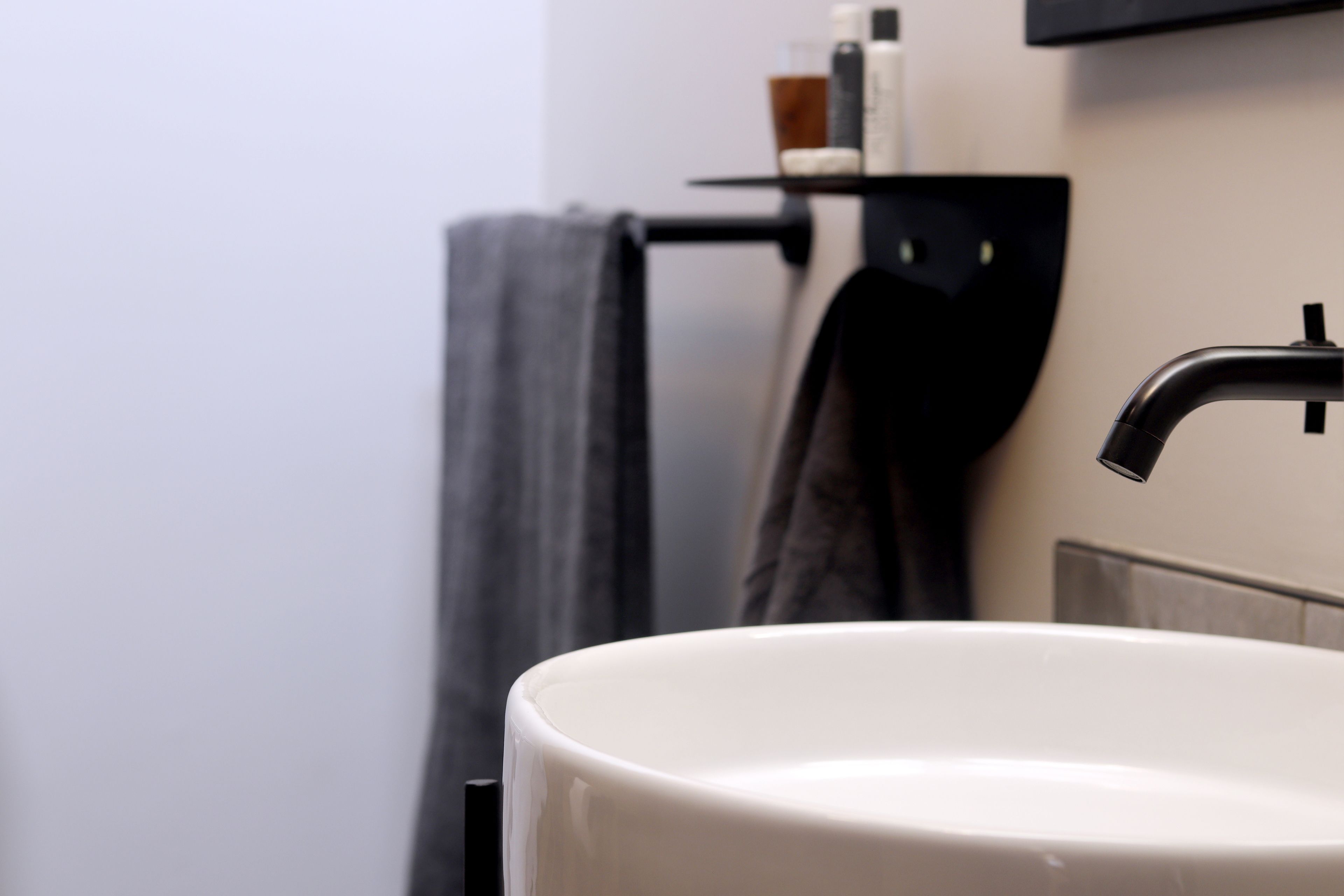 A bathroom with a white sink, a black faucet, and a towel rack with a towel.