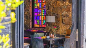 Een gezellig eetgedeelte met een stenen muur, een kleurrijk glas-in-loodraam en een moderne zithoek.