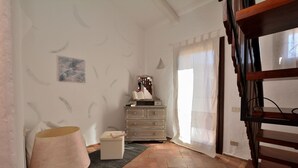 A room with a wooden floor, a lamp, a dresser, and a mirror. - Bloom 37 (Arzachena)