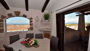 Un comedor con una mesa dispuesta para cuatro personas, un arco de piedra, una planta en maceta y vistas al paisaje.