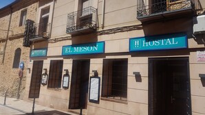 Un edificio con un letrero que dice "EL MESÓN" y otro letrero que indica "HOSTAL".