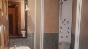 Un baño con ducha de vidrio, lavamanos e inodoro.