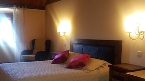 Un dormitorio con una cama, dos lámparas de pared, una silla, un escritorio y una ventana con cortinas.