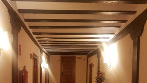Un pasillo con suelo de cuadros, vigas de madera en el techo y una puerta de madera al final.