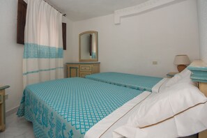 Un dormitorio con dos camas, un aparador de madera, un espejo y una lámpara.