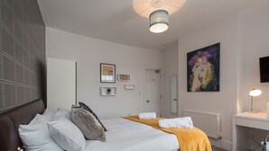 Une chambre à coucher comprenant un lit, un bureau, une chaise, un radiateur, une porte et un tableau accroché au mur.