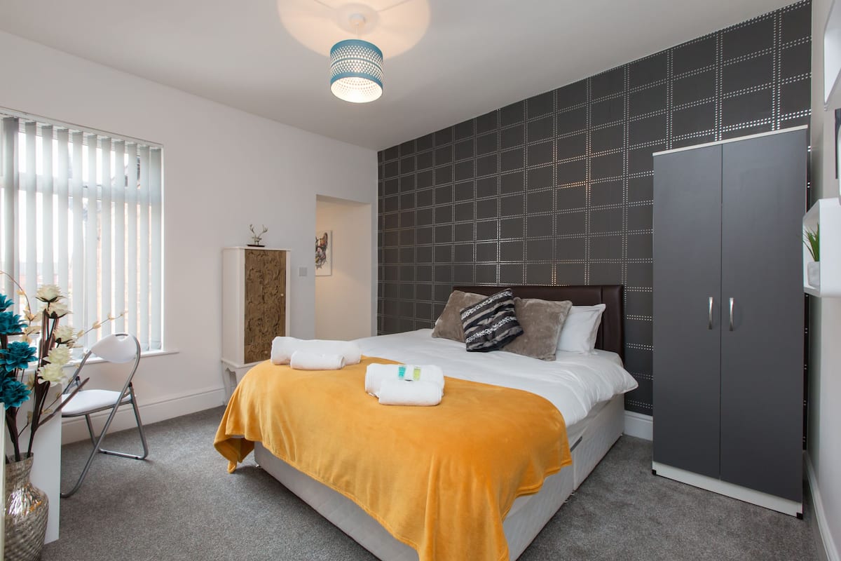 Een moderne slaapkamer met een groot bed, een garderobe en een raam met zonwering.
