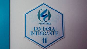 Een zeshoekig bord met een logo en de tekst 'OASIA FANTASIA INTRIGANTE 11'.