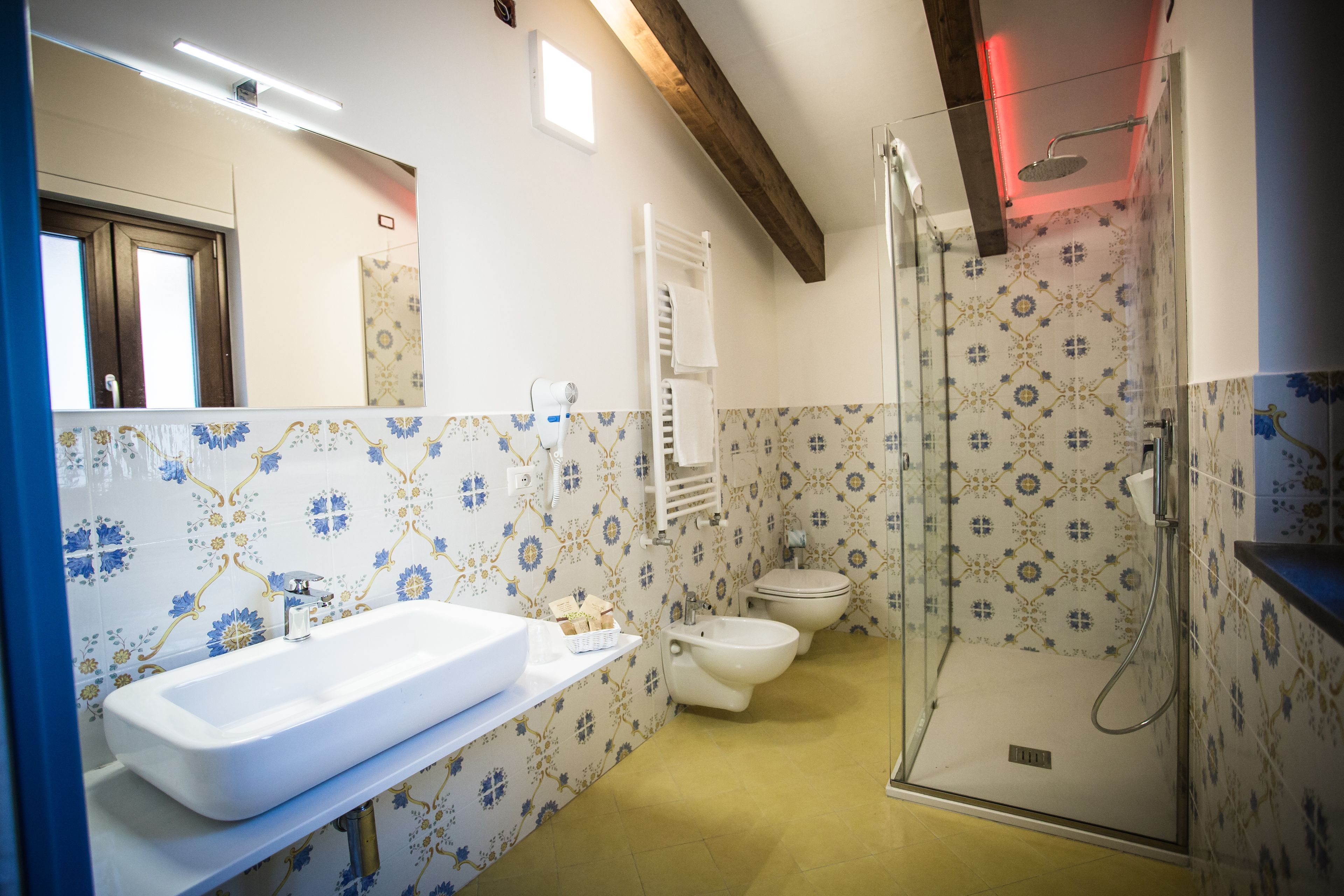 A bathroom with a large white sink, a bidet, a toilet, and a glass-enclosed shower.