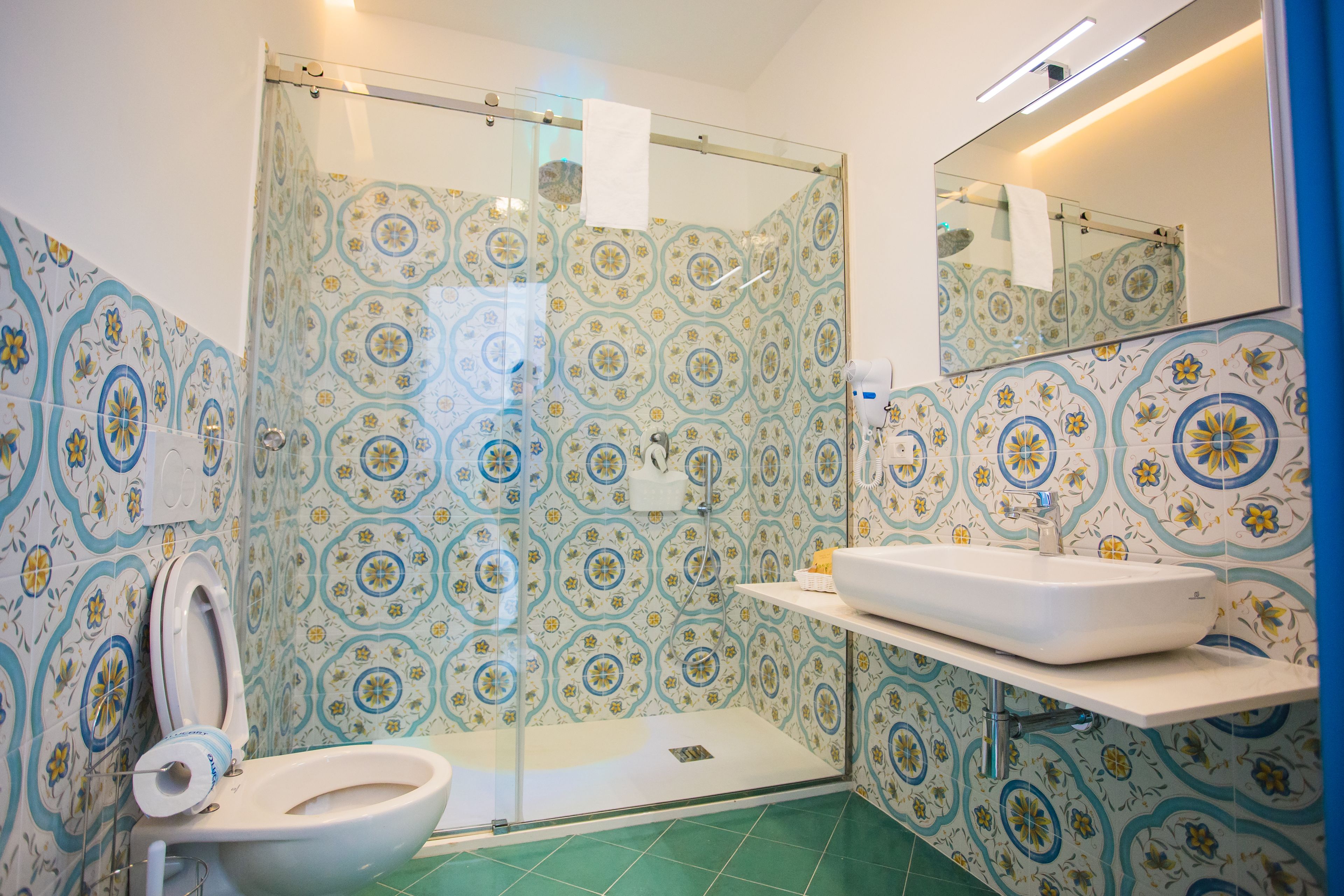 A bathroom with a shower, toilet, and sink, all with patterned tiles.