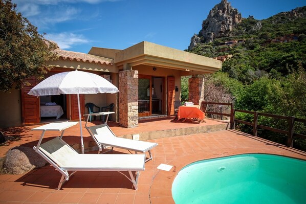 A villa with a swimming pool, outdoor seating, and a mountain view.