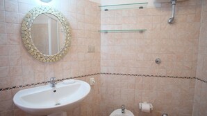 A bathroom with a sink, bidet, toilet, and a mirror with a mosaic frame. - Sole 1 (Trinità d'Agultu e Vignola)