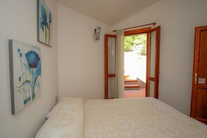 Une chambre avec un lit, une porte en bois et une vue sur un espace extérieur.