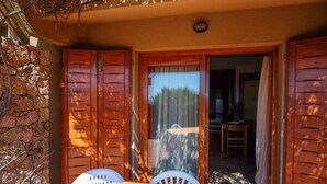 Une porte en bois avec un panneau de verre, un mur en pierre et une table jaune avec des chaises blanches.
