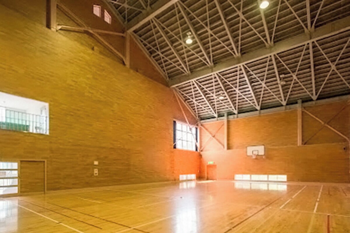 Une salle de sport intérieure dotée d’un haut plafond, d’un plancher en bois et d’un panier de basket.