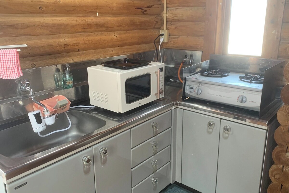 A compact kitchen with a microwave, gas stove, and a sink with a dish rack.