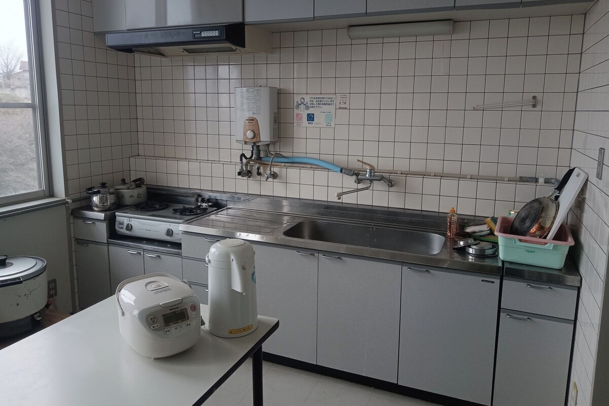 Une cuisine équipée d’une cuisinière, d’un évier et d’un chauffe-eau.