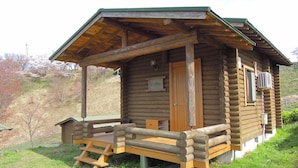 Uma cabana de madeira com varanda, porta e uma pequena janela.