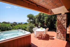 A hot tub with a view of the sea, a stone wall, and a table with chairs. - Sole 3 (Trinità d'Agultu e Vignola)