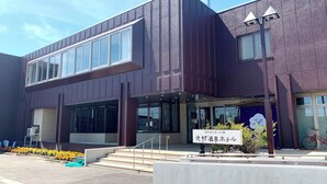 A modern building with large windows, a signboard, and a bicycle parked outside. - Kitamura Onsen Hotel (Iwamizawa)