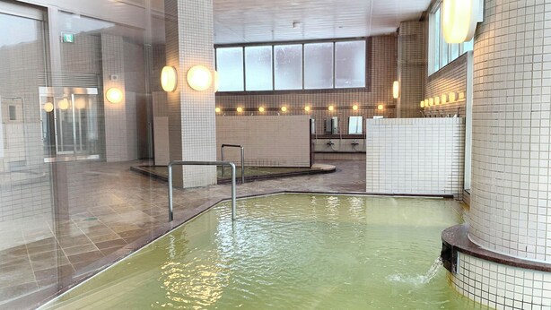 A swimming pool with a tiled interior, a glass wall, and a metal railing. - Kitamura Onsen Hotel (Iwamizawa)