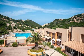 A resort with a swimming pool, palm trees, and a mountainous backdrop. - Green 1 (Trinità d'Agultu e Vignola)
