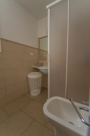 Une salle de bain avec un lavabo, un miroir et une poubelle blanche.