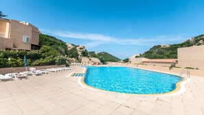 A swimming pool with lounge chairs and umbrellas, surrounded by hills and buildings. - Green 3 (Trinità d'Agultu e Vignola)