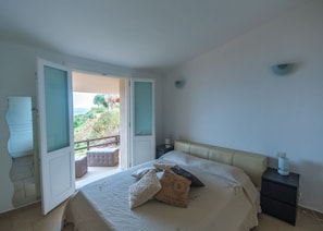 Une chambre à coucher comprenant un lit, une table de chevet, une commode, une fenêtre et une vue sur l’extérieur.