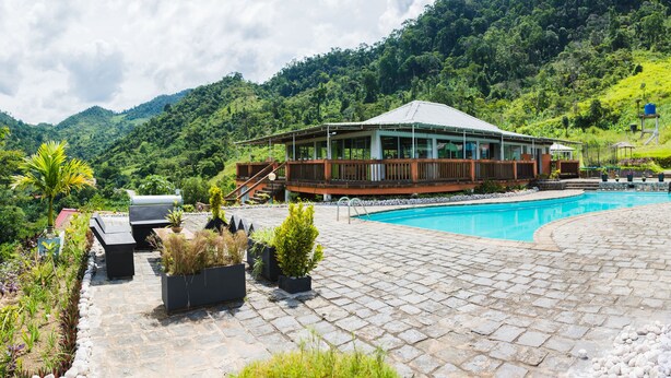 A resort with a swimming pool, a wooden deck, and a mountain backdrop. - Karibotel (Antananarivo)