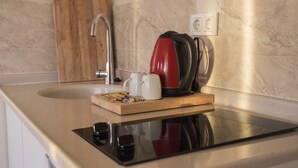 A kitchen with a stainless steel sink, a wooden cutting board with a mug and a red kettle, and a marble backsplash. - A Apart Hotels Ankara Beytepe (Ankara)