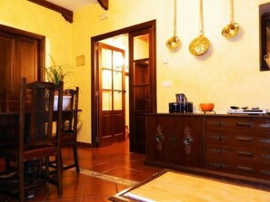 Una cocina con armarios de madera, una mesa de comedor y ollas colgantes.