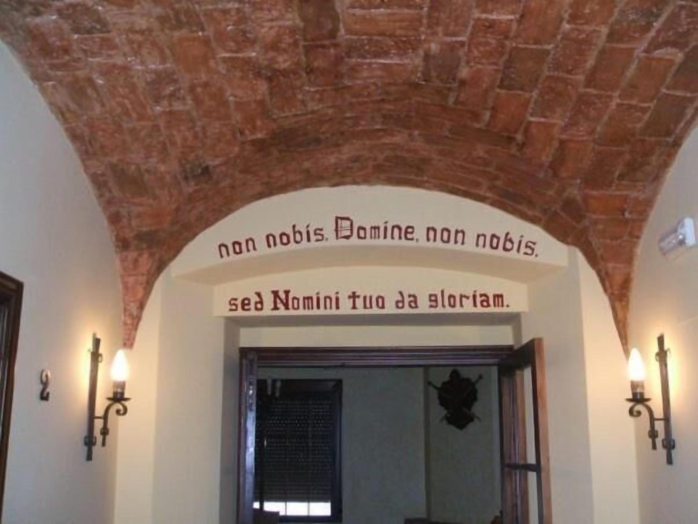 An arched doorway with a sign above it in a building with brick walls and wall-mounted lights.