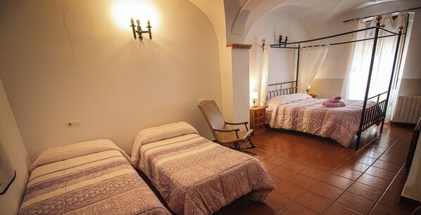 A bedroom with two single beds, a chair, a bedside table, and a window with curtains. - La Casa de los Templarios (Puebla de Alcocer)