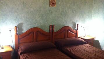 Un dormitorio con estructura de cama de madera, dos almohadas y una mesita de noche con lámpara.