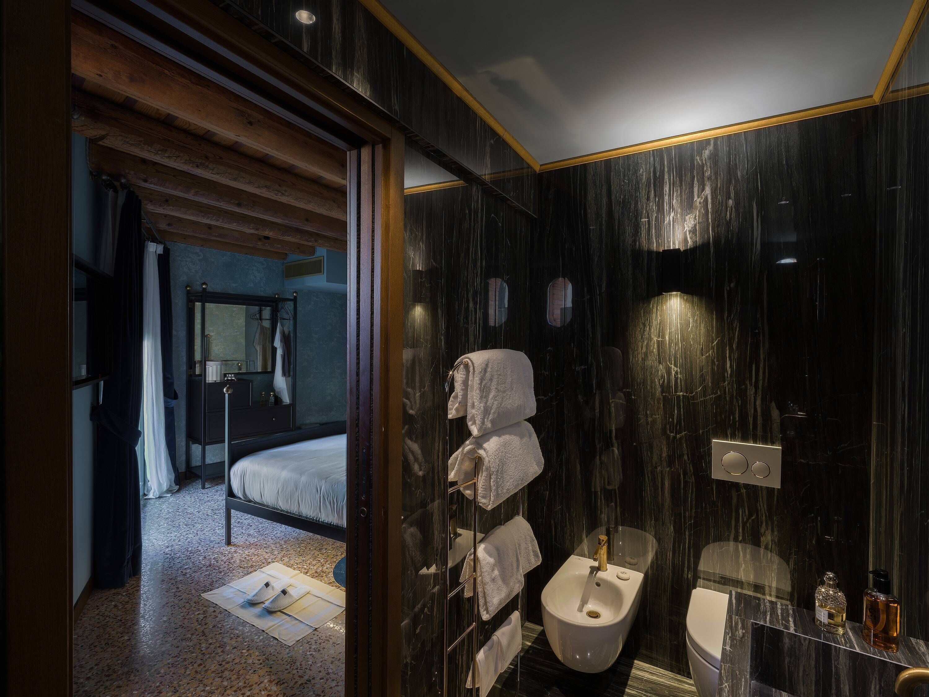 Ein modernes Badezimmer mit einer Bio-Toilette, einem Waschbecken und einem Spiegel. Ein Bett ist im angrenzenden Raum zu sehen.