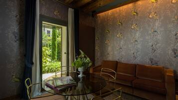 Una habitación con una mesa de vidrio, un sofá marrón y papel tapiz con motivos florales.