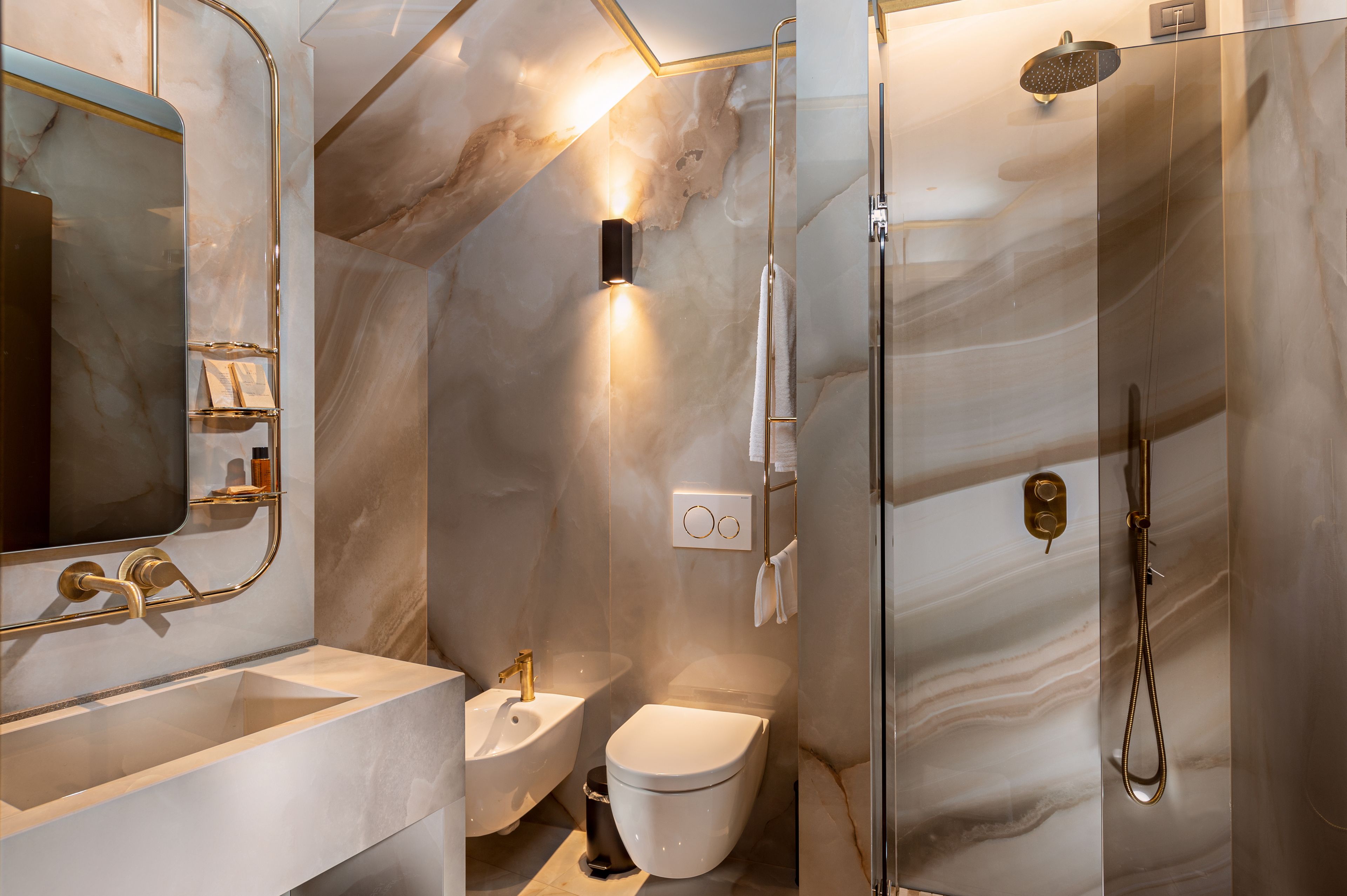 Un baño moderno con pared de mármol, un lavabo, un inodoro y una ducha.