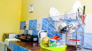Een keuken met een afwasscherm, een kookplaat en diverse keukengerei op het aanrecht.