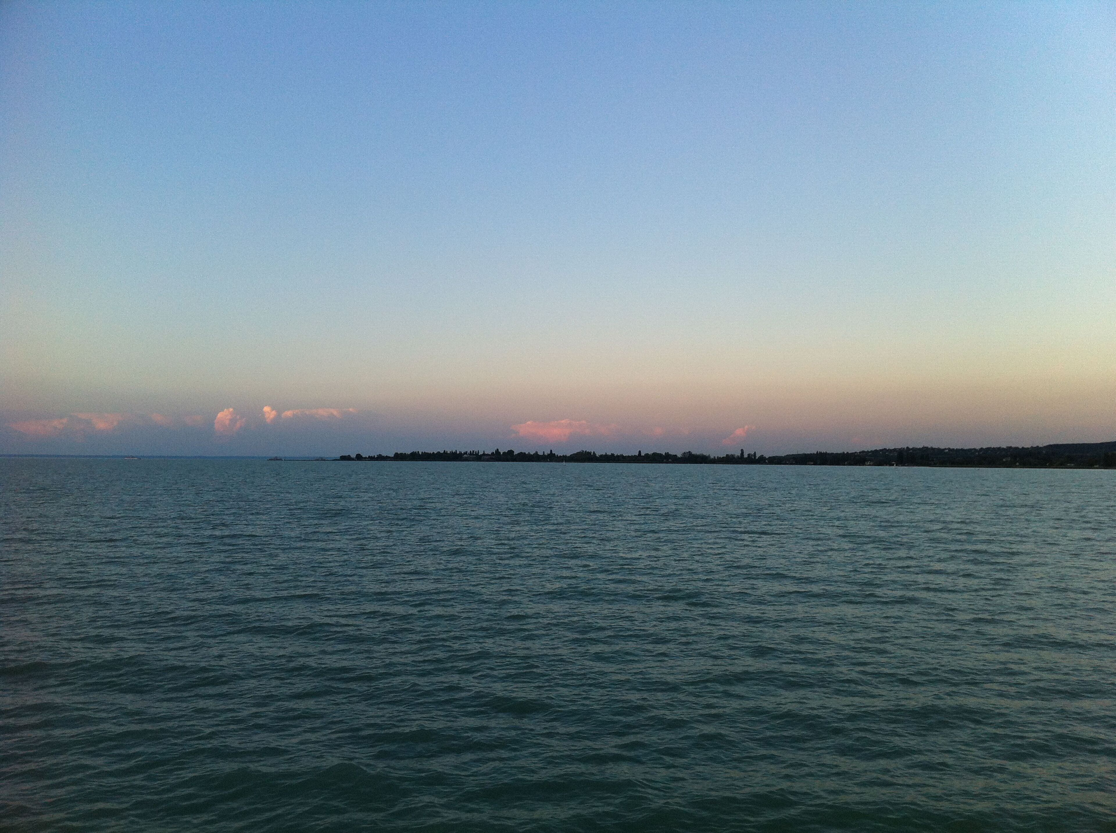 A calm sea with a distant shoreline and a clear sky.