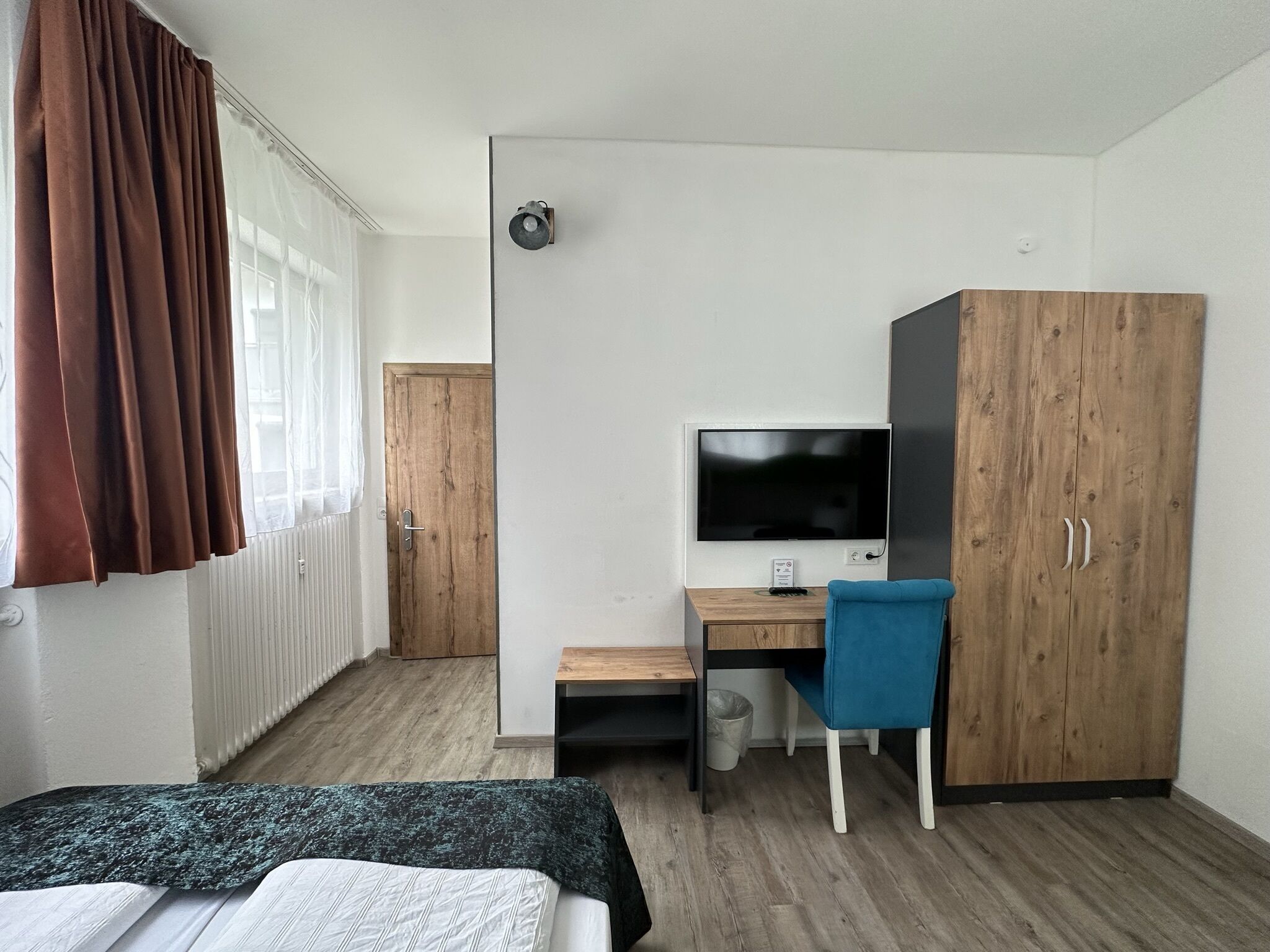 Ein Schlafzimmer mit einem Bett, einem Schreibtisch mit Computer, einem Fernseher und einem Kleiderschrank.