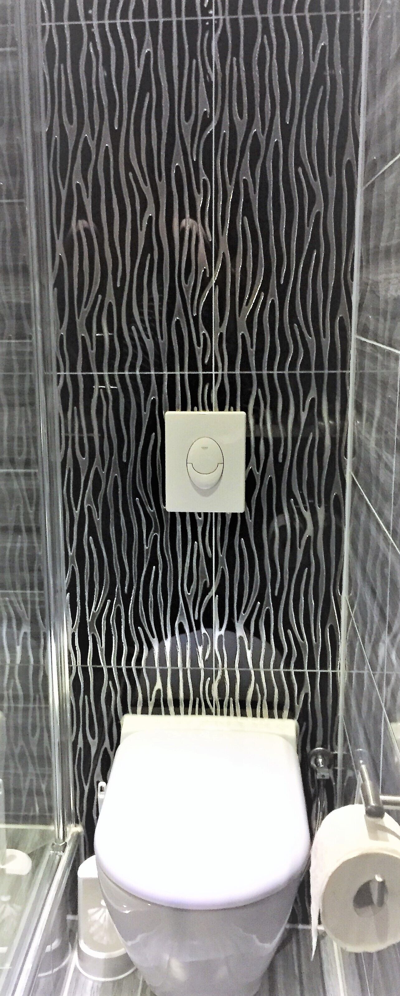 A bathroom with a patterned wall, a toilet, and a hand dryer.