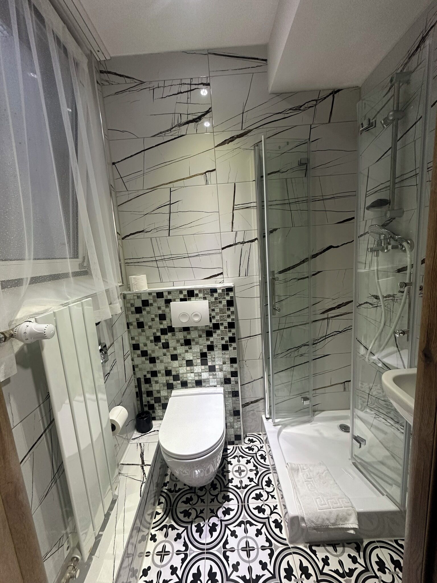 Ein kleines Badezimmer mit Toilette, Dusche und einer gläsernen Duschkabine.