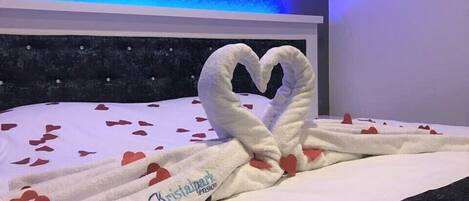 Una cama con una toalla dispuesta en forma de corazón y un logotipo en las toallas.